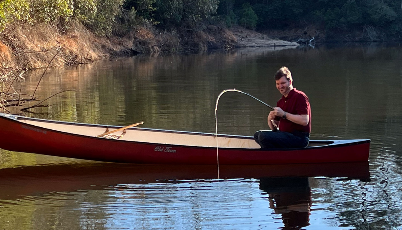 The SandViking on a secluded pond in a canoe with a bent rod and a trophy bass on the hook!